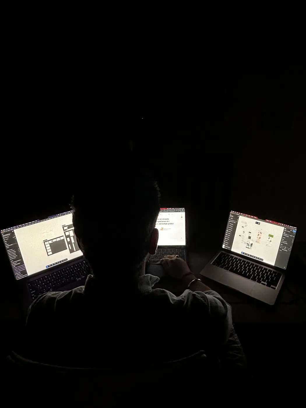 Two laptops glowing in a dark room