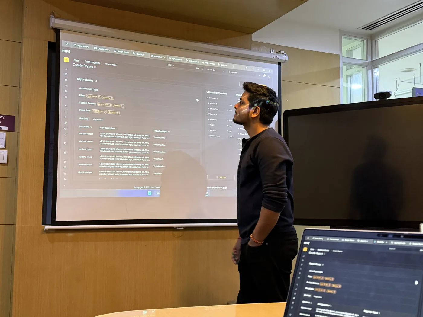 Anuraj pointing at a dashboard on the meeting-room screen