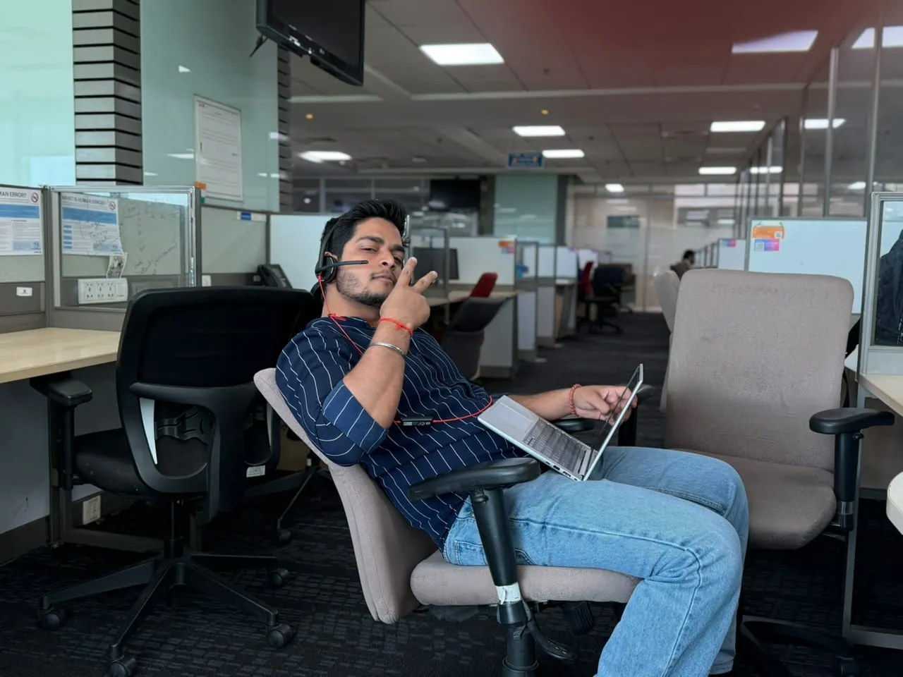 Anuraj working on a laptop with a headset in a busy office